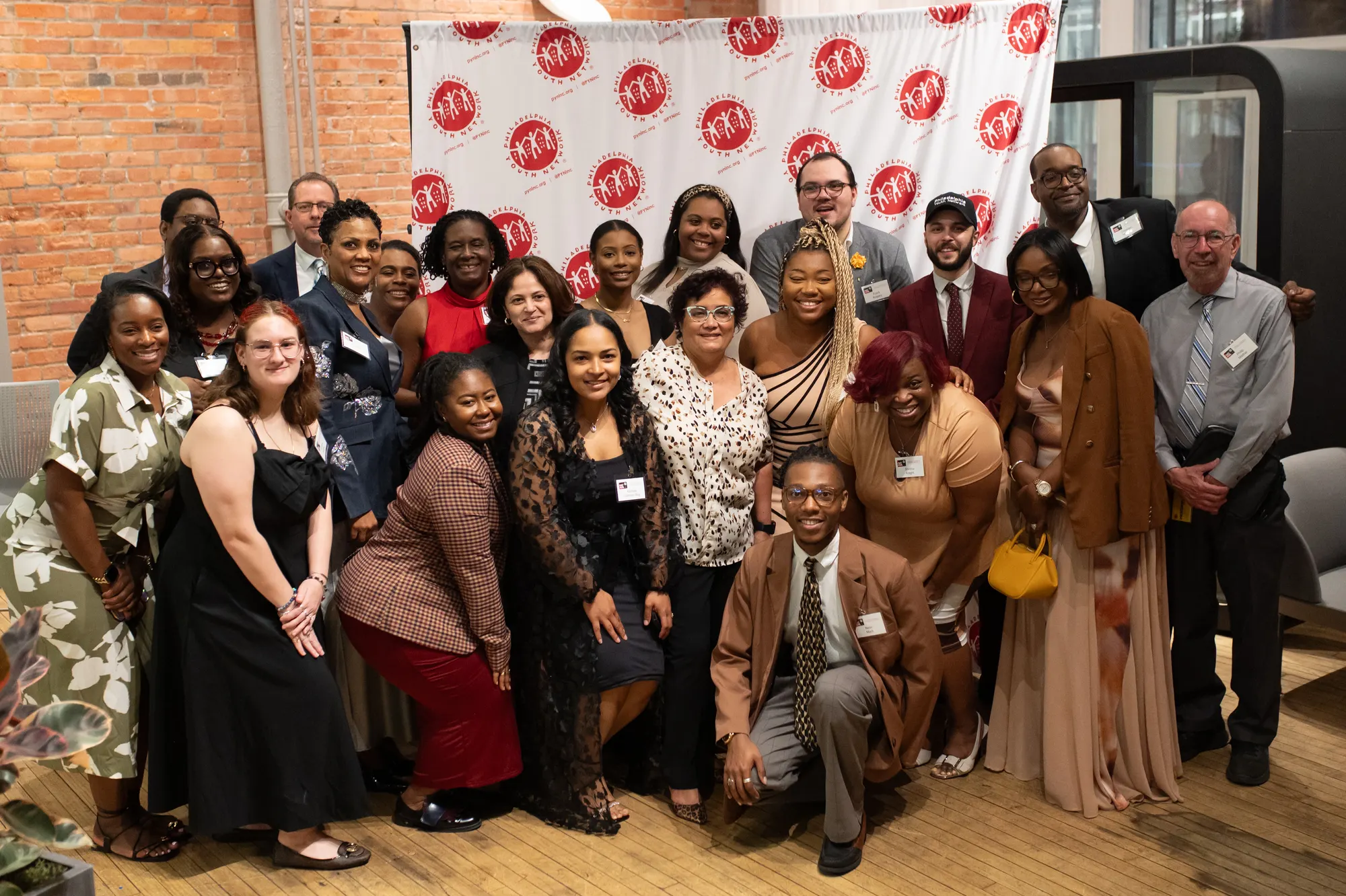 The full group posed together in front of a branded step-and-repeat.