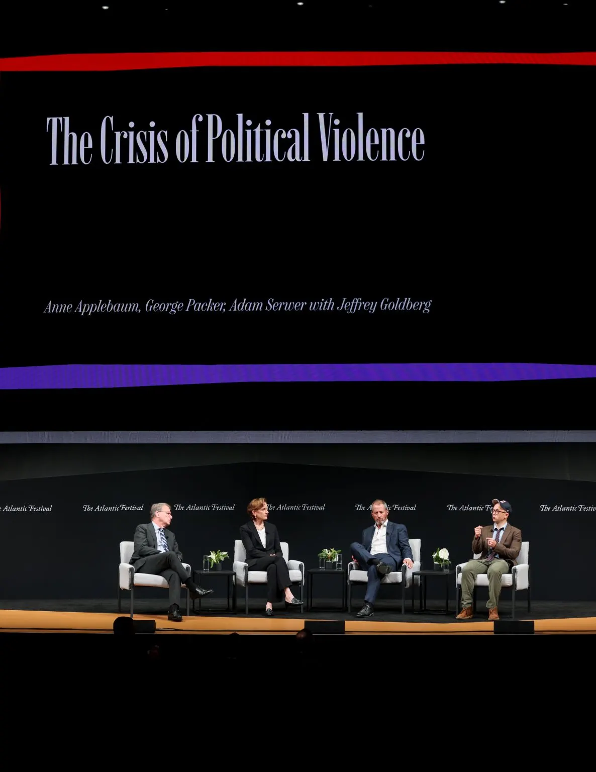 Four panelists on a dark stage under the title The Crisis of Political Violence.