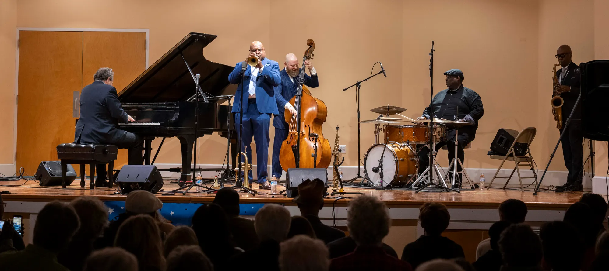 A vocalist at the microphone with the upright bassist behind them.