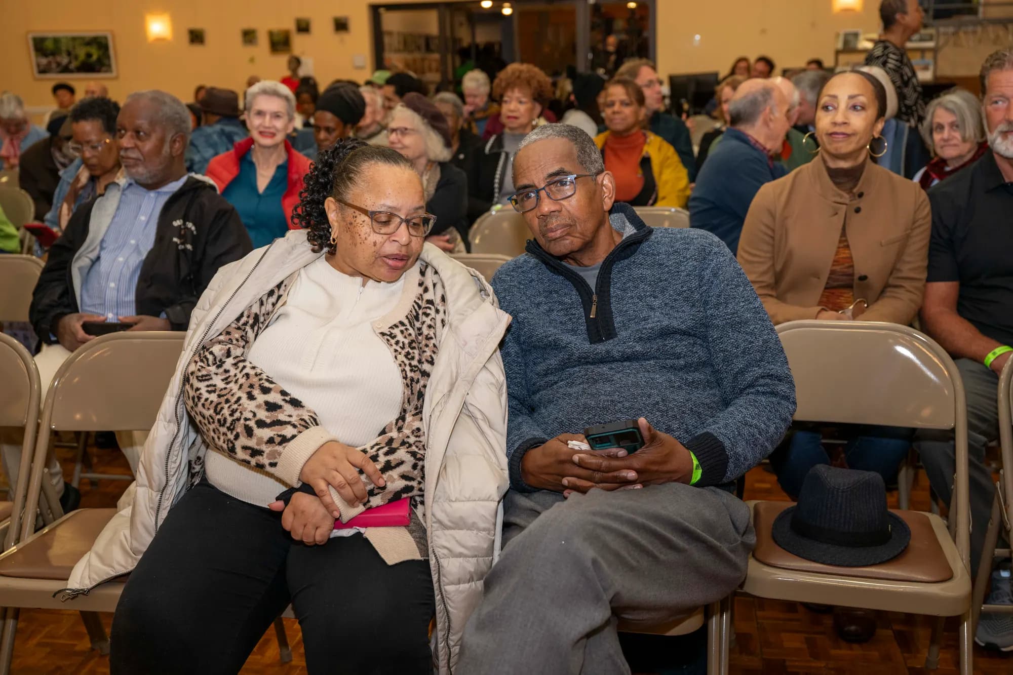 Two audience members seated close together in a packed hall.