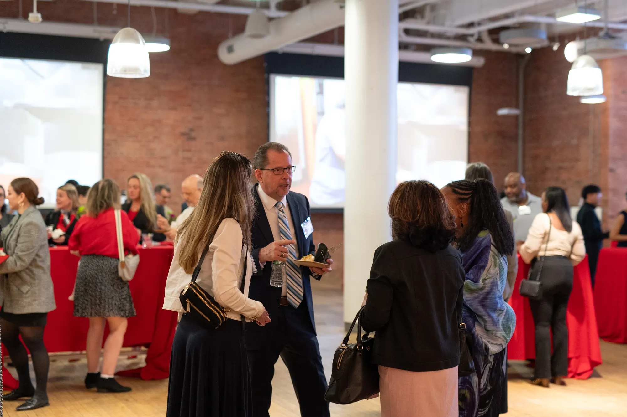 Guests mingling with drinks at a loft reception.