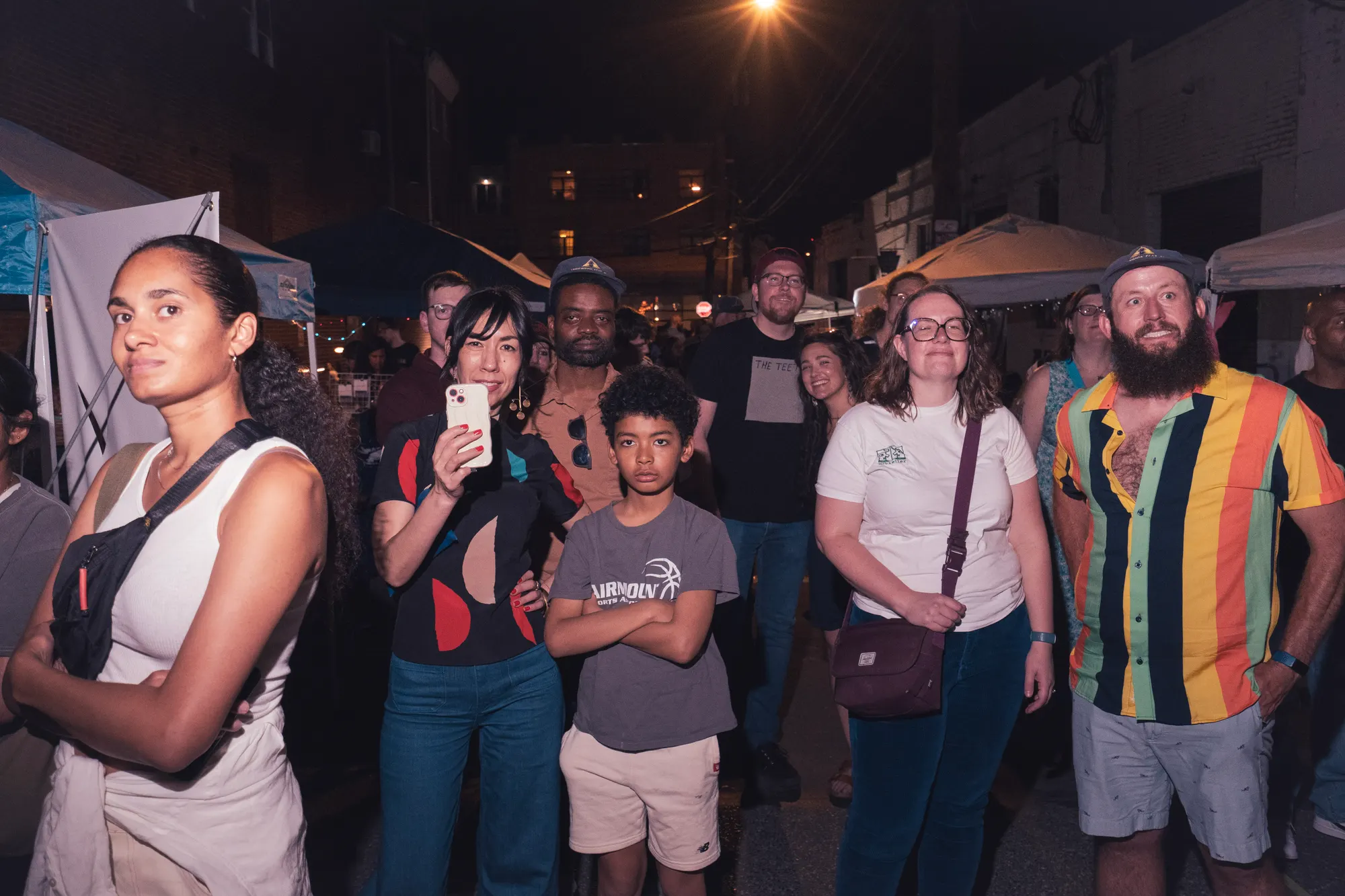 The festival crowd filling the street after dark, phones raised.