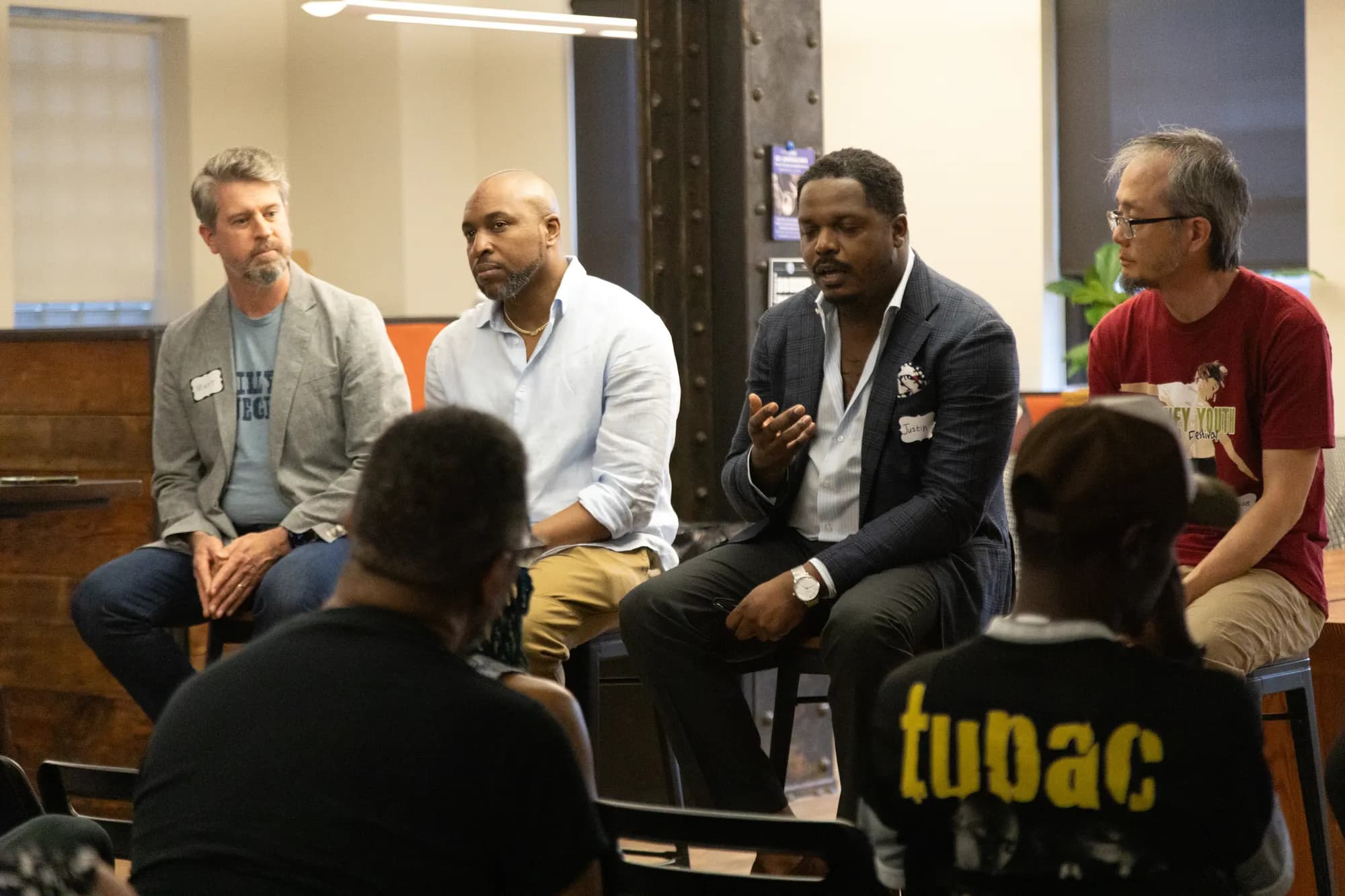 Four panelists in conversation, one gesturing as he makes a point.