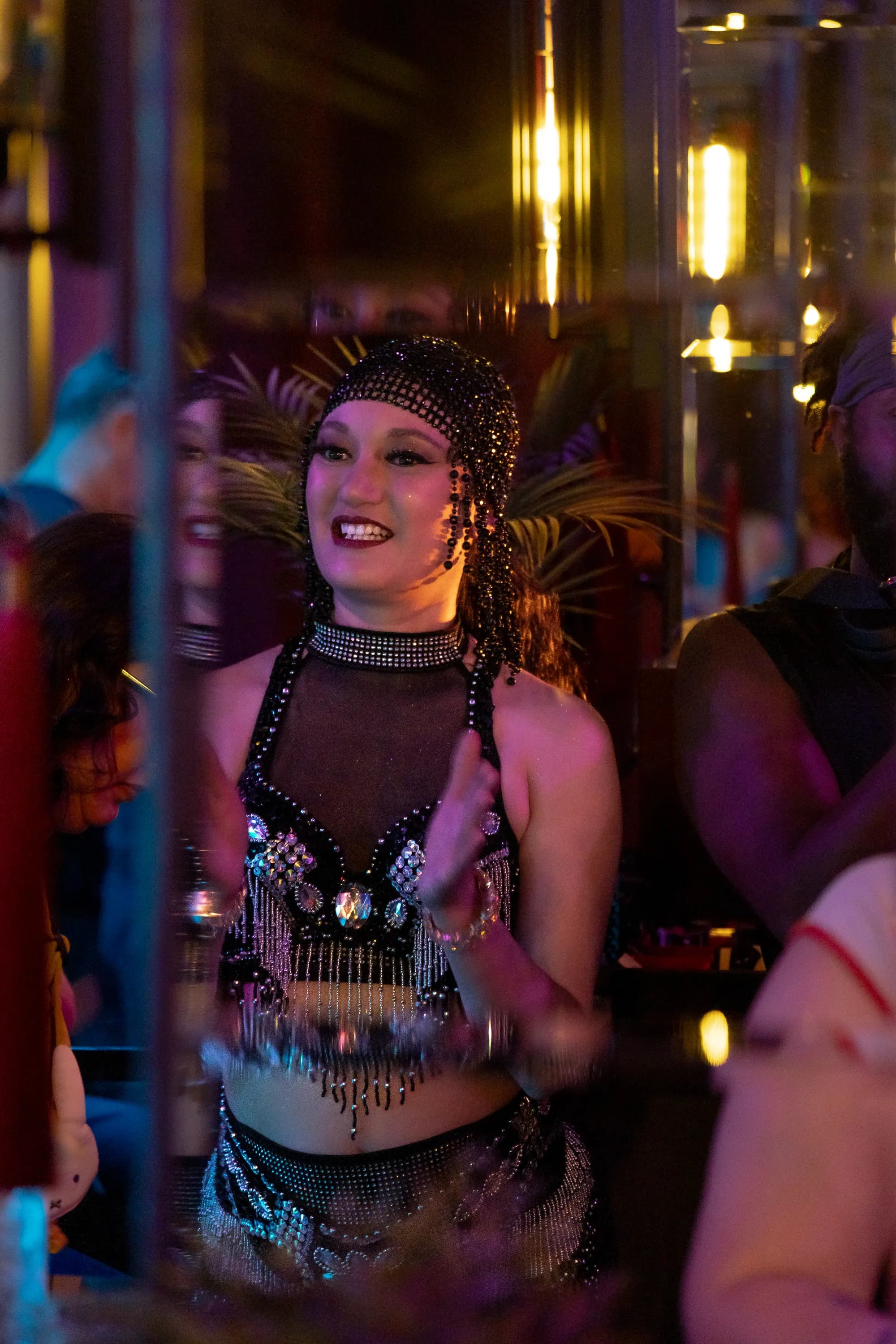 A dancer in a beaded headpiece smiling through the crowd.