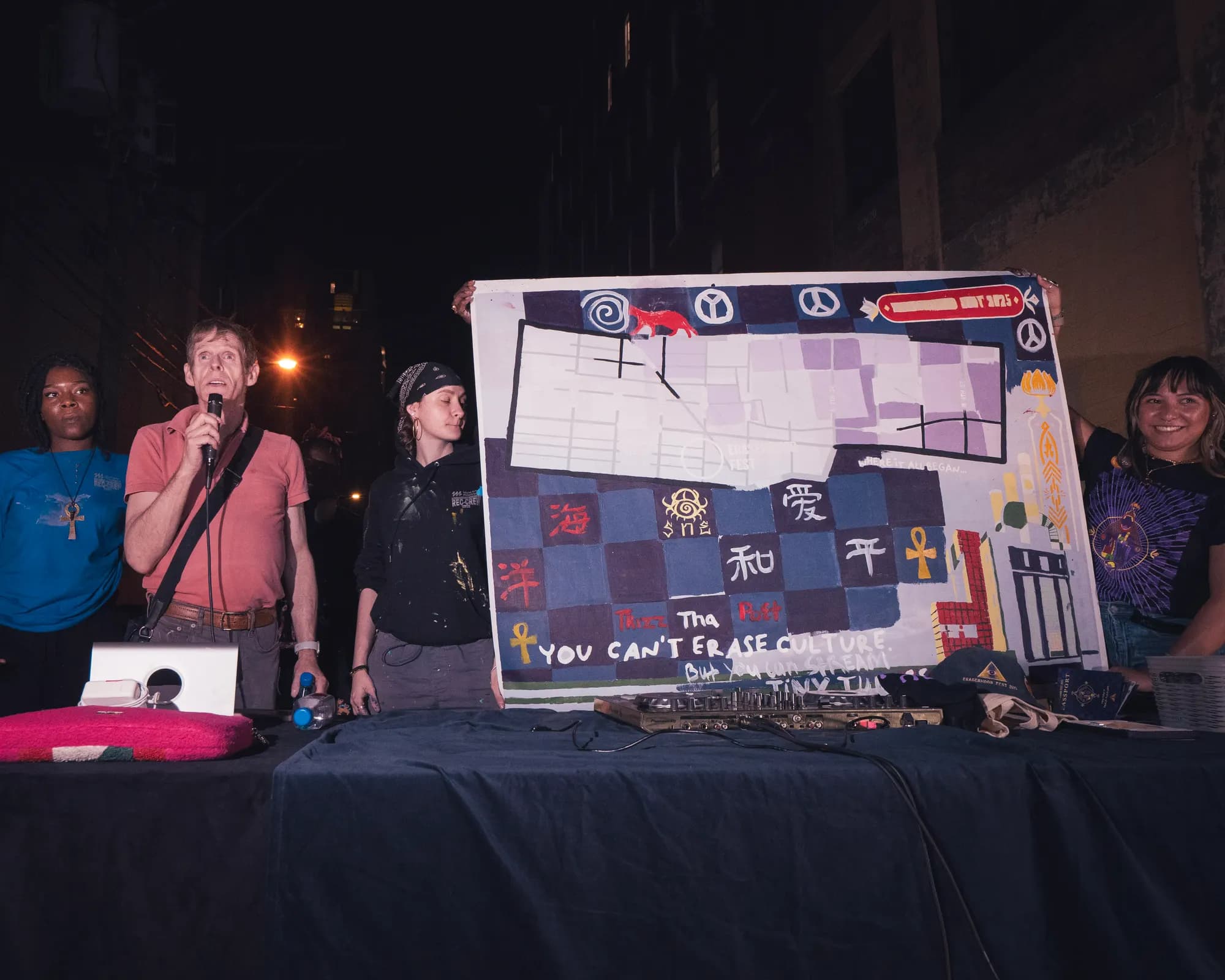 Two hosts presenting a hand-lettered board to the crowd.