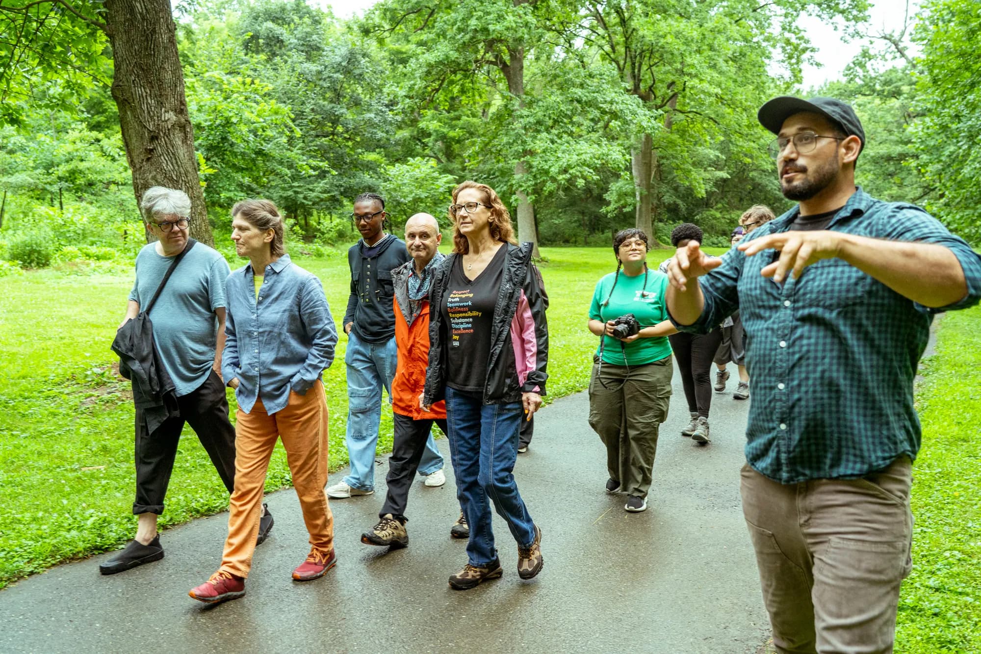 A guided walk moving along a wooded park path on an overcast morning.