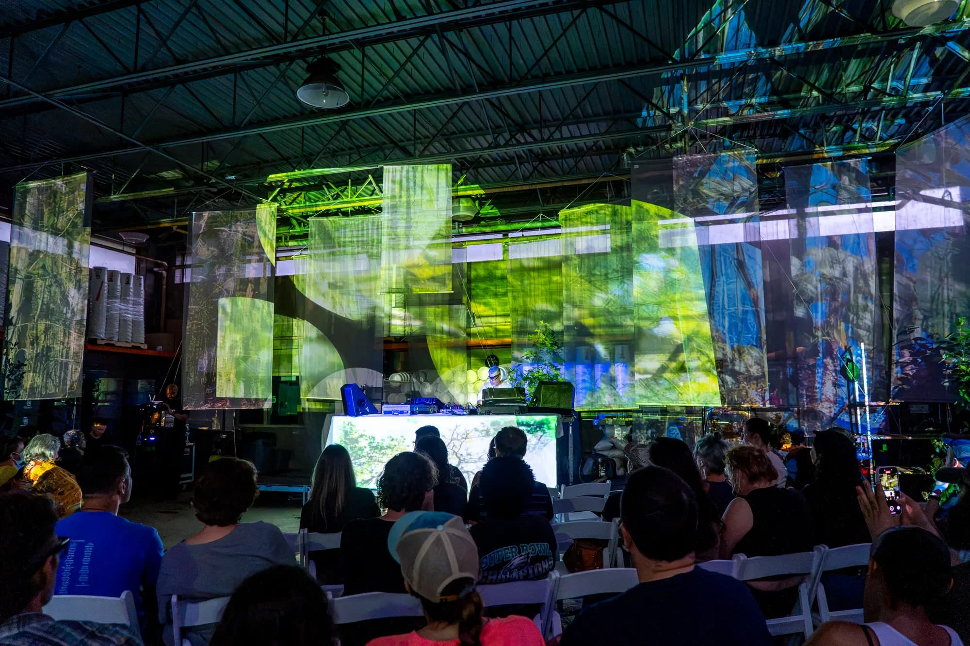 Layered green and blue projections filling the width of the warehouse screen.