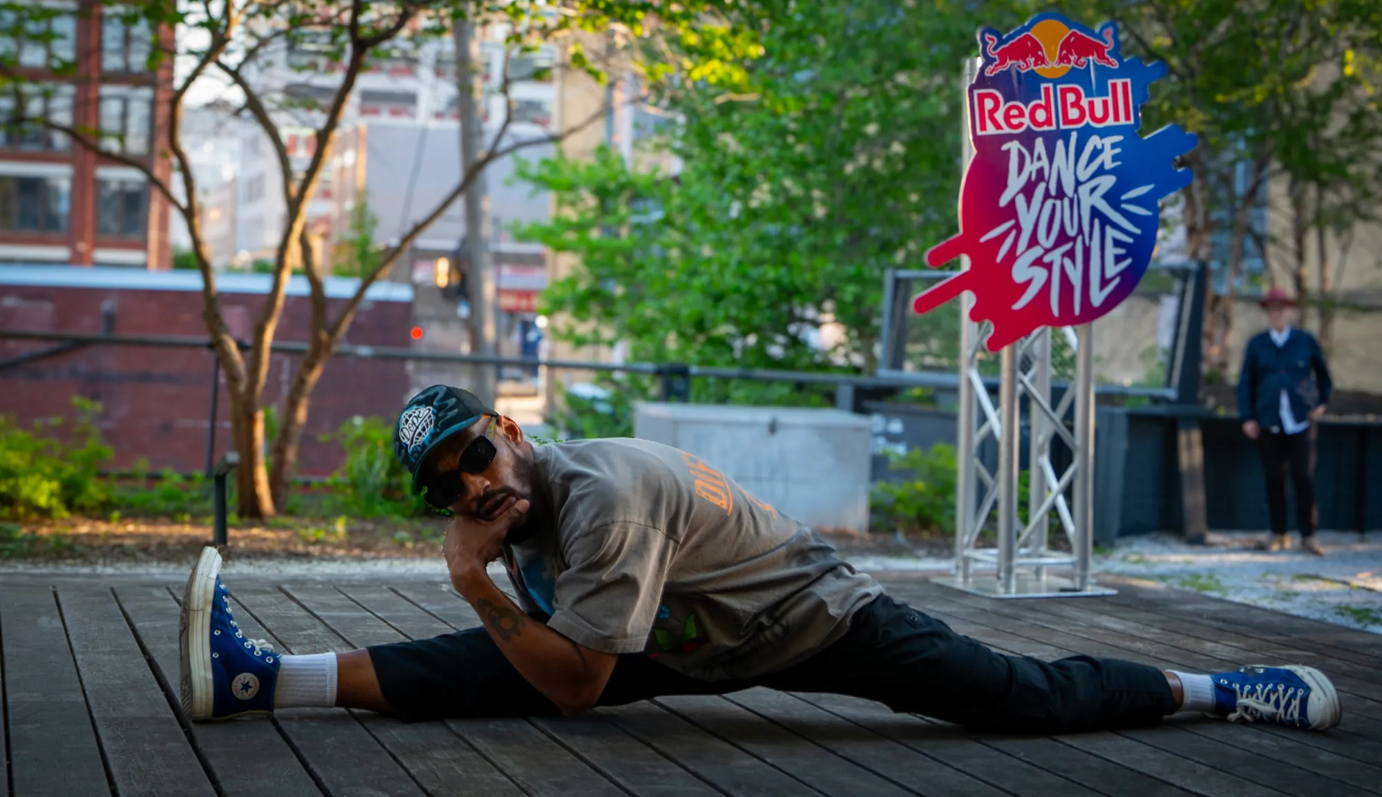 A dancer holding the splits on the wooden deck beside the Red Bull Dance Your Style sign.