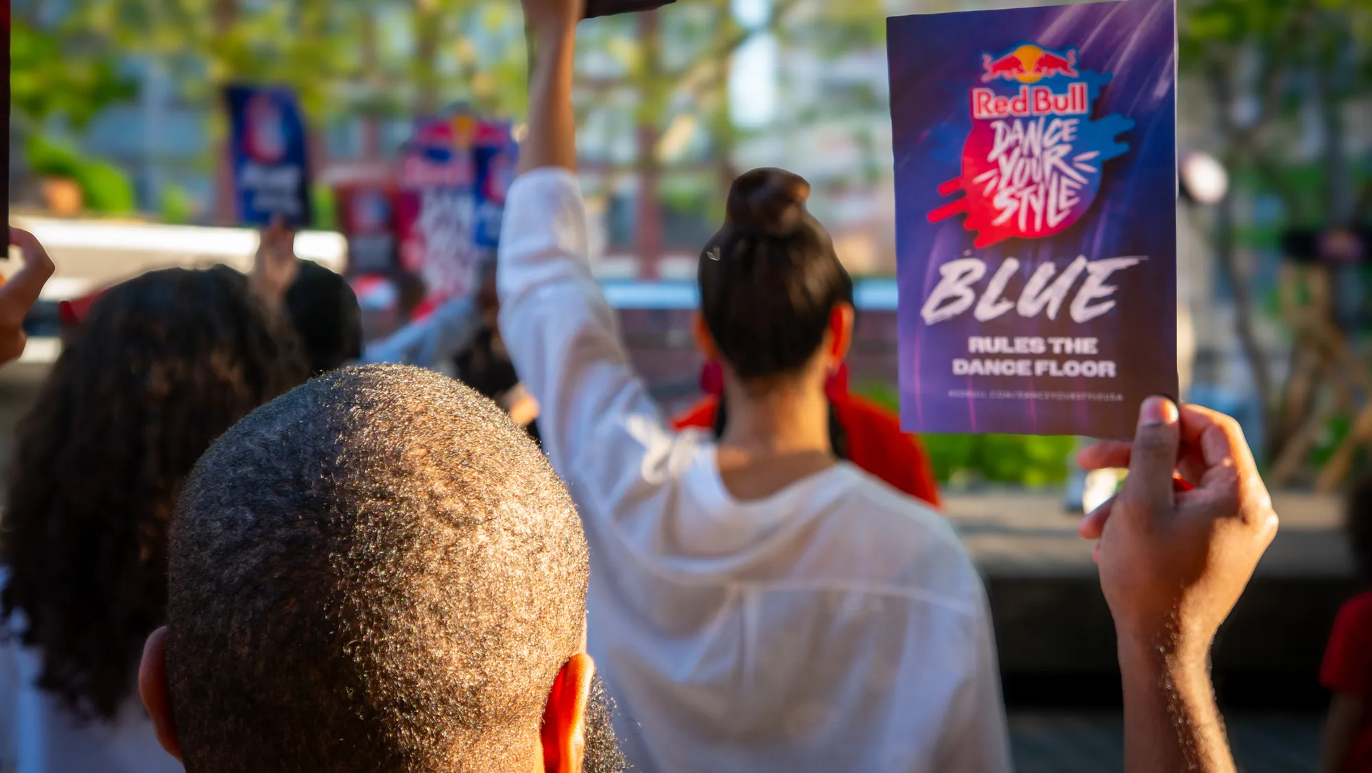 The crowd holding up Blue Rules the Dance Floor cards to vote in the dance battle.