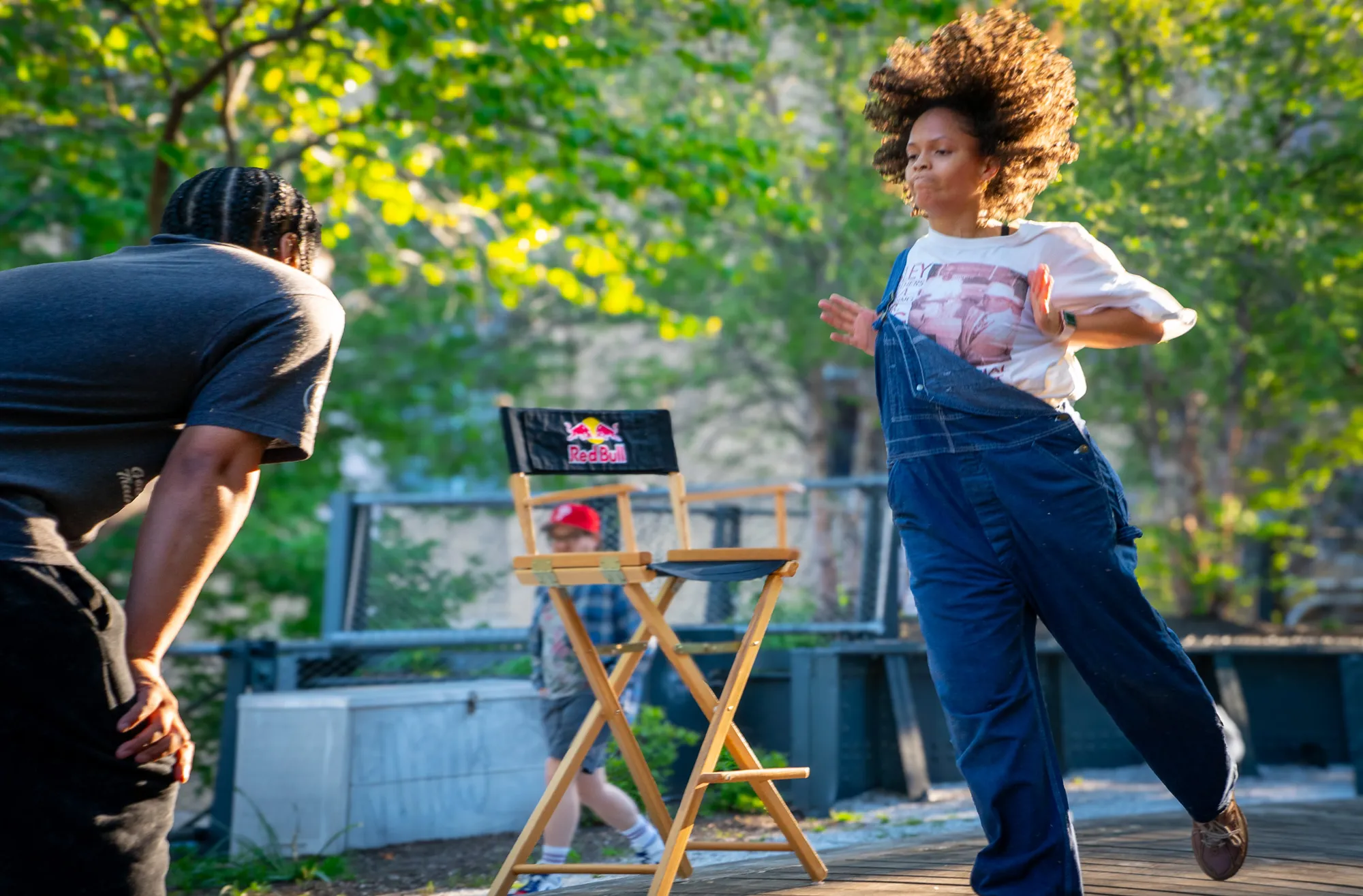A dancer in denim overalls mid-spin, hair flying, in the golden-hour light.